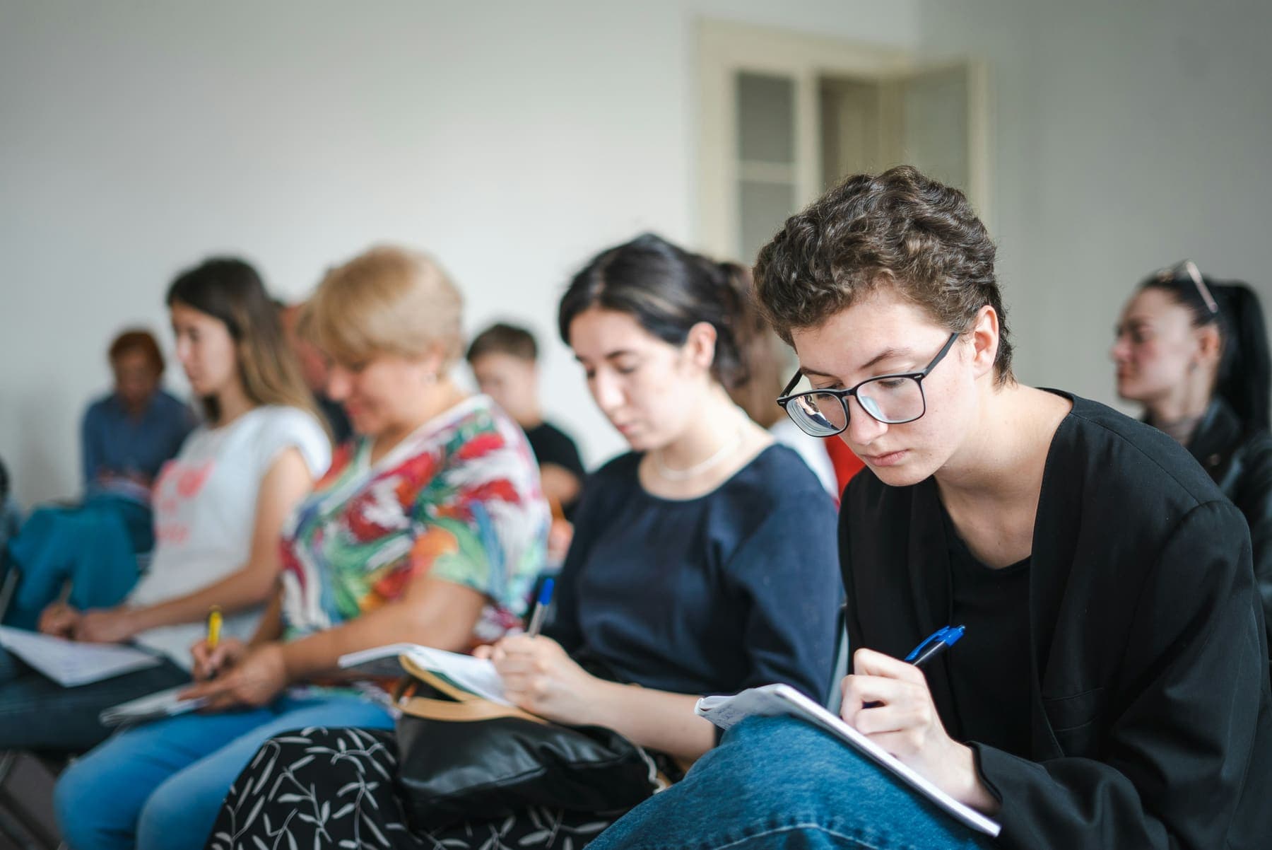 Young people sitting in rows taking notes during a training session run by an organisation